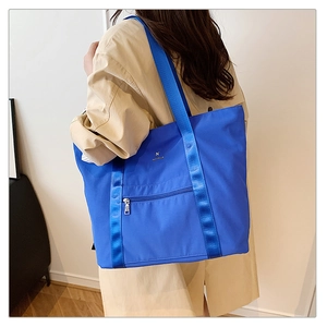 Détail du sac cabas bleu roi en tissu Oxford avec poche latérale et logo métallique