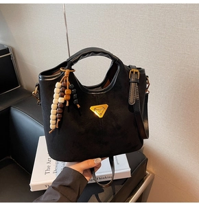 Gros plan détaillé du sac seau noir mat avec logo doré et pompon perlé