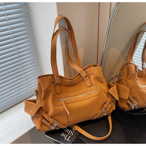 Detailed close-up of yellow faux leather tote with metal zippers and rivet strap accents