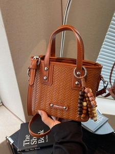 Sac à main vintage marron avec texture tressée, doubles anses et breloque perlée