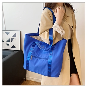 Vue détaillée d'un grand sac fourre-tout bleu en nylon avec poignées et poche zippée