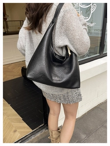 Détail du grand sac à bandoulière noir mat avec élégant accessoire de breloque en perles