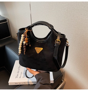 Gros plan du sac seau noir mat avec poignée circulaire et breloque en perles tressées