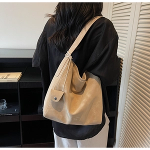 Minimalist beige suede tote bag with small hanging coin purse shown on a bookshelf
