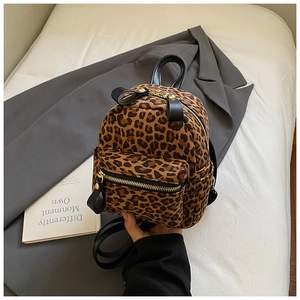 Close-up of leopard print mini backpack with gold zippers and textured canvas material