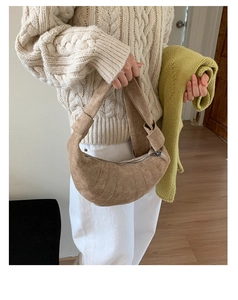Détail d'un sac demi-lune en daim marron avec nœuds décoratifs et fermeture éclair