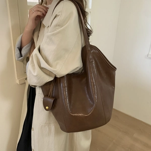Detail of a dark brown glossy leather tote bag shown on model for daily commute style