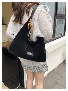 Vue arrière du mannequin portant un grand sac hobo noir mat avec pendentif perlé