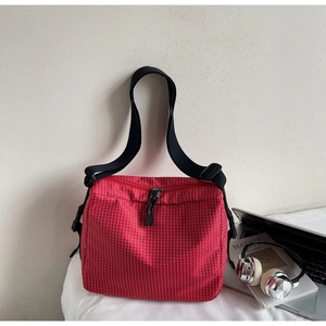 Detail of red checkered canvas tote with adjustable black strap and durable nylon fabric