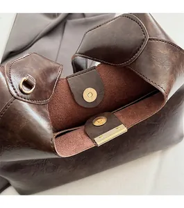Detail of dark brown vintage faux leather tote showing the secure magnetic clasp closure