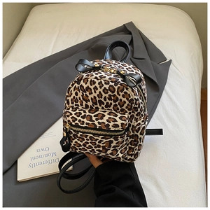 Detail view of mini leopard print backpack featuring gold hardware and canvas texture