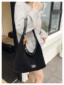Détail du sac cabas en suédine noire avec breloque ethnique et empiècement en cuir
