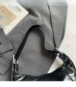 Detail of glossy PU leather shoulder bag with silver rings and wide strap on grey suit