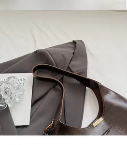 Detailed shot of dark brown retro underarm bag with glossy leather and gold buckle