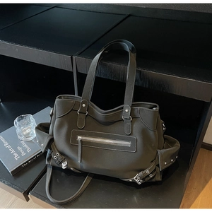 Detail of a large black tote bag with zipper pocket and adjustable metal side buckles