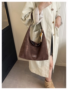 Détail du sac hobo marron foncé avec pendentif en perles rétro et étiquette logo