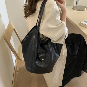 Close-up of the polished black leather tote bag with metallic buckle detail on side
