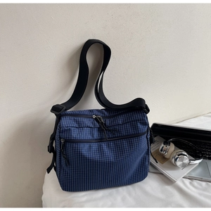 Detail of blue plaid canvas tote with two front zipper pockets and black strap