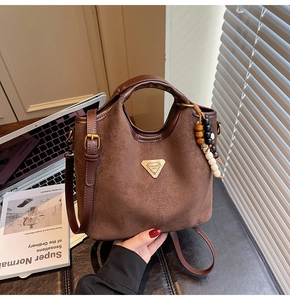 Détail du sac seau en daim marron avec bordures en cuir et pendentif à perles décoratif