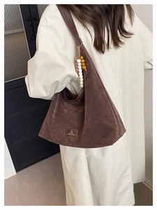 Détail d'un sac cabas vintage en daim marron avec bandoulière en cuir et perles