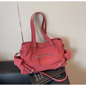 Detail of a large coral red tote bag showing multiple pockets and metallic buckles