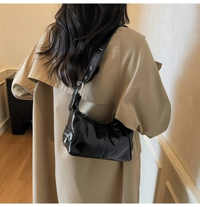 Close-up of glossy black patent leather shoulder bag with sleek silver metallic zippers