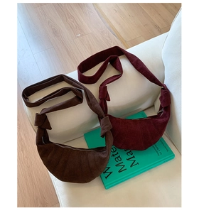 Vue détaillée des sacs croissants en daim marron et rouge sur un canapé blanc
