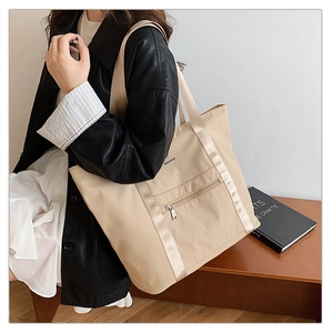 Détail du sac cabas en nylon beige avec zip argenté et sangle renforcée sur mannequin