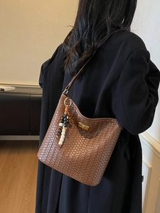 Braune geflochtene Eimer-Tasche mit Goldverschluss und Perlenanhänger am Model
