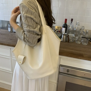 Detailed view of large off-white PU tote bag worn by model in a cozy kitchen setting