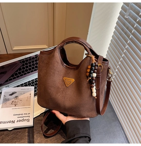 Gros plan sur un sac seau marron givré avec perles en bois et logo en métal doré