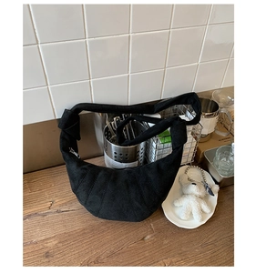 Détail d'un sac bandoulière croissant noir plissé en daim avec breloque ours mignon