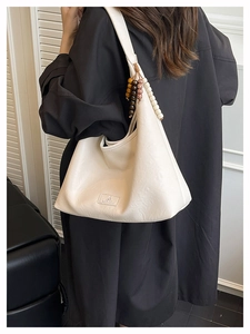 Sac hobo blanc cassé avec texture mate vintage et breloque en perles sur la bandoulière
