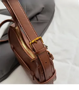Close-up of premium brown leather crossbody bag with vintage gold metal buckle and stitching