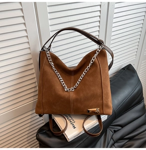 Detail of vintage brown suede tote with silver chunky chain and heart charm detail