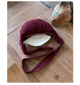 Vue de dessus sac croissant rouge foncé en suédine avec détail de bandoulière nouée