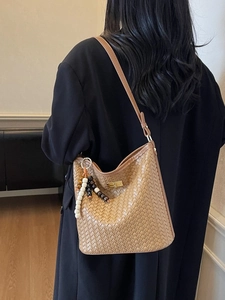 Braune gewebte Beuteltasche mit Perlenanhänger, präsentiert an einem Model im Mantel
