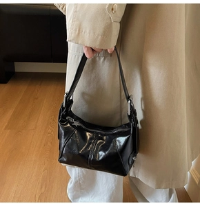Detail of glossy black patent leather bag with a silver star pendant zipper pull