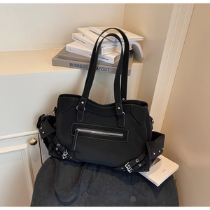 Detail view of black commuter tote bag with multi-pockets and metal buckle on soft stool