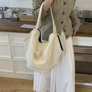Detail of minimalist cream-colored hobo shoulder bag with textured leather and leaf charm