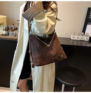 Brown suede tote bag with contrast stitching and silver chain detail on model