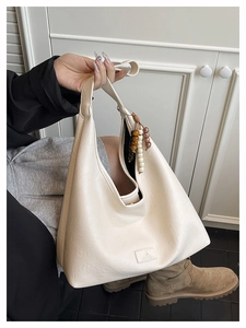 Détail du sac hobo blanc cassé avec texture mate et breloque en perles décorative