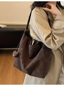 Large vintage coffee tote bag in matte leather worn by a model in a beige coat