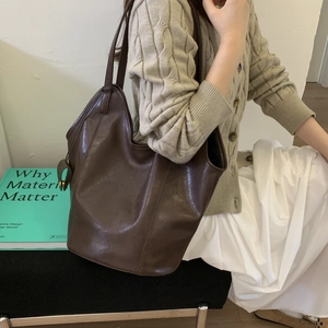 Detail of dark brown vintage leather tote bag styled with a beige knit outfit