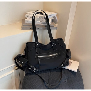 Detail view of black tote bag with silver zippers, buckles, and rivets in a punk style