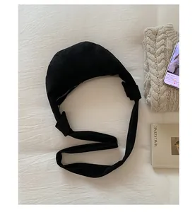 Gros plan du sac bandoulière croissant noir avec bandoulière nouée sur un tissu doux