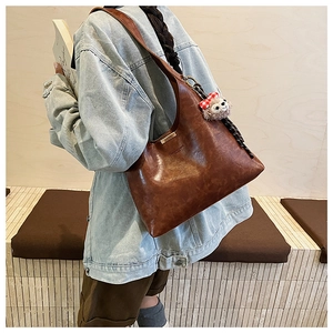 Detail of a deep brown shiny leather hobo bag with a cute plush animal charm accessory