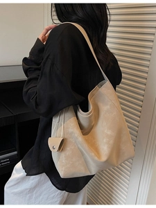 Minimalist beige large tote bag with soft shoulder straps shown on a model in a modern room