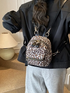 Chic leopard print mini backpack with gold zippers shown on model in a warm indoor setting