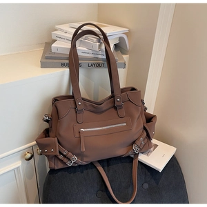 Detail of vintage matte brown tote bag with metal rivets and decorative side straps
